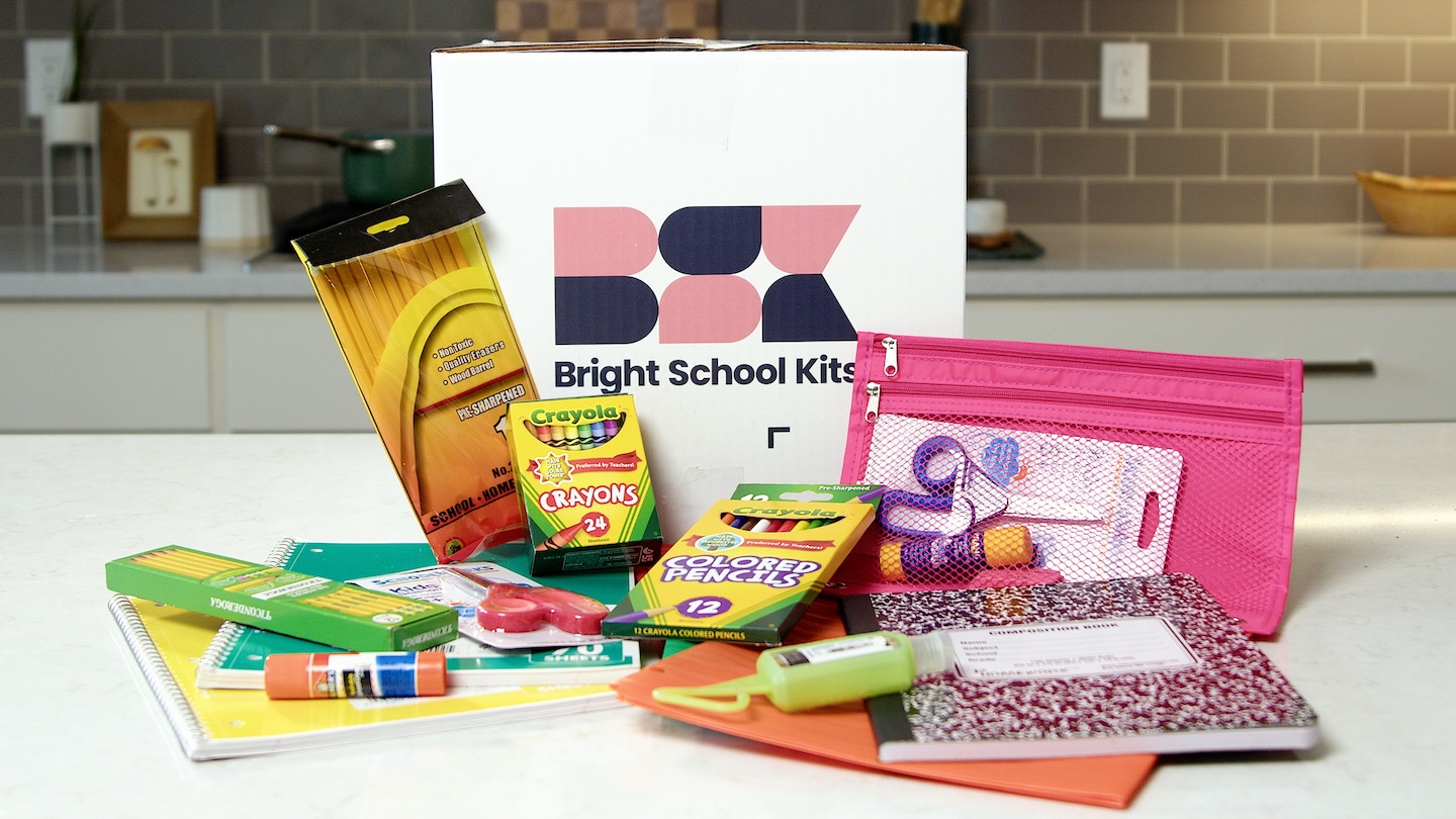 example of a school supply kit featuring supplies like crayons, pencils, a pink pencil pouch, notebook, folders, and more